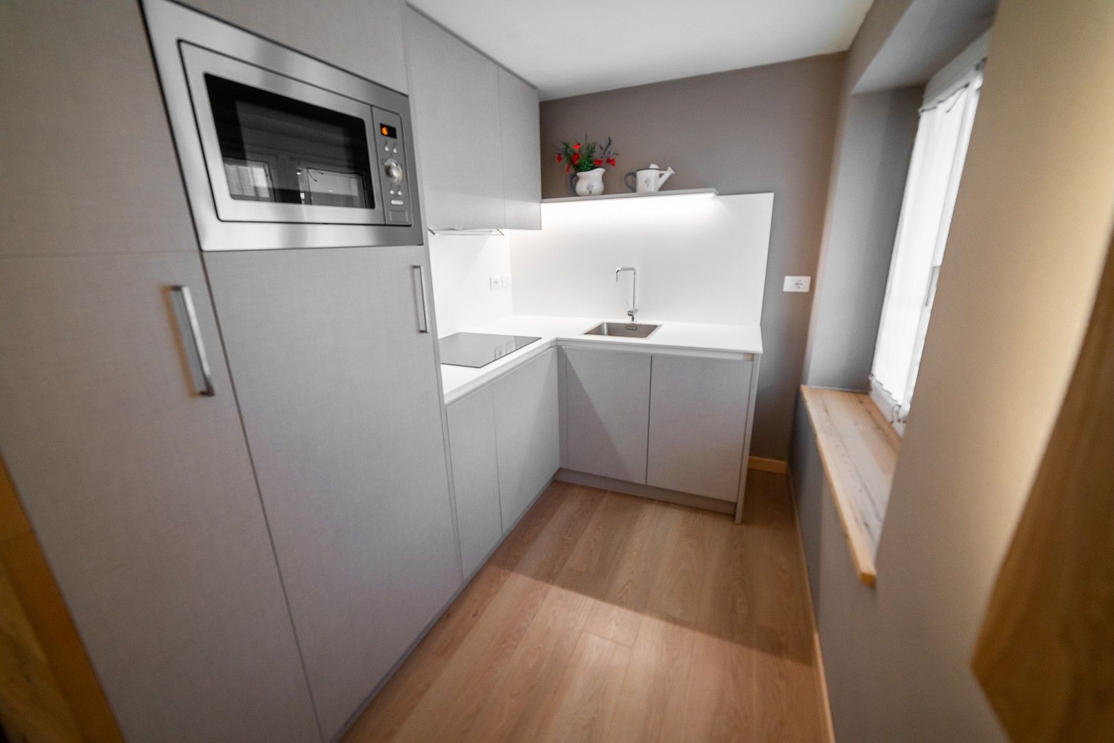 A compact kitchen with a built-in microwave, a sink, and a small countertop area.