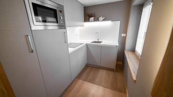 A compact kitchen with a built-in microwave, a sink, and a small countertop area.
