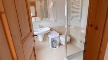 Un bagno con doccia, lavandino, WC e specchio.