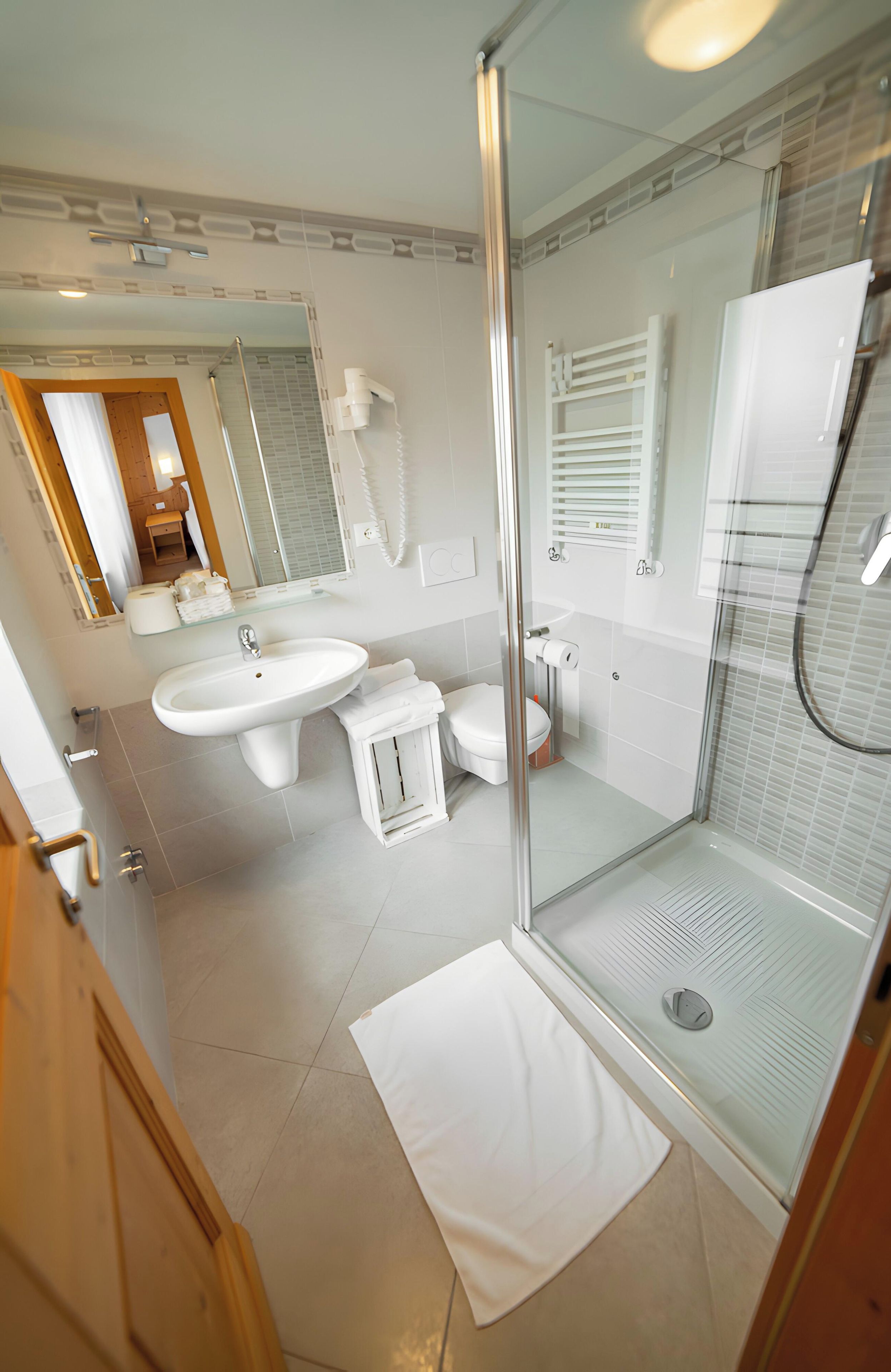 Un bagno moderno con cabina doccia in vetro, due lavabi, un water e un mobile vanitario con specchio.