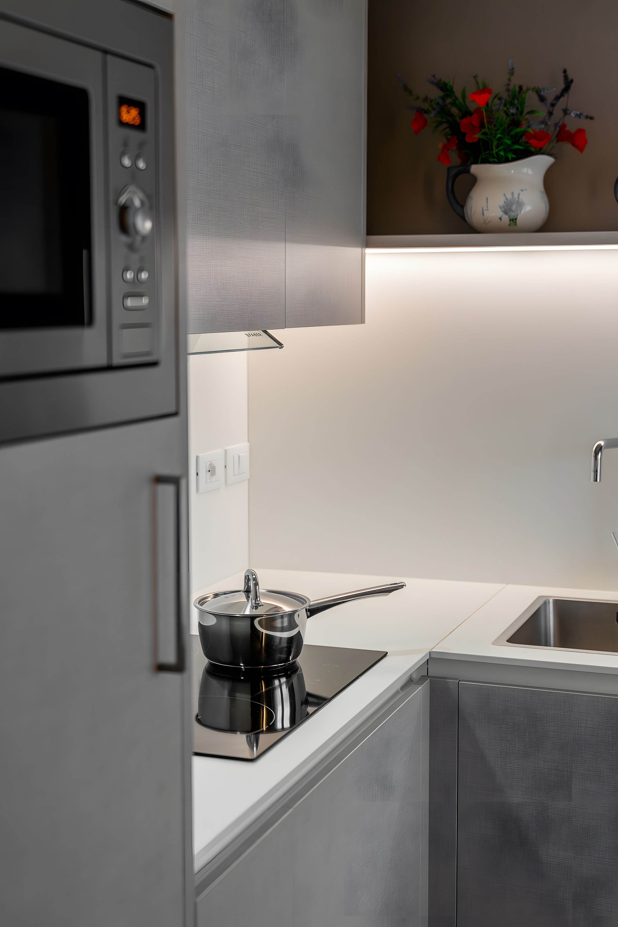 Een moderne keuken met een magnetron, fornuis en spoelbak.