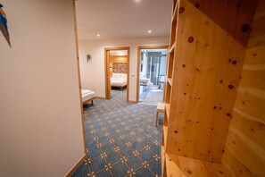A narrow hallway with a patterned floor leading to a bedroom with a bed and a bathroom with a sink and toilet. - ‘Cirmolo’ Room with Mountain View, Shared Terrace and Wi-Fi (San Sebastiano)