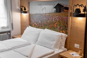 Ein Bett mit weißen Leinen, einem Holz-Kopfteil und einer Wandleuchte.