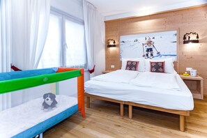A hotel room with a bed, a crib, a wooden headboard, a nightstand, and a wall-mounted decoration. - Sciatore Room with Mountain View, Shared Terrace and Wi-Fi (San Sebastiano)