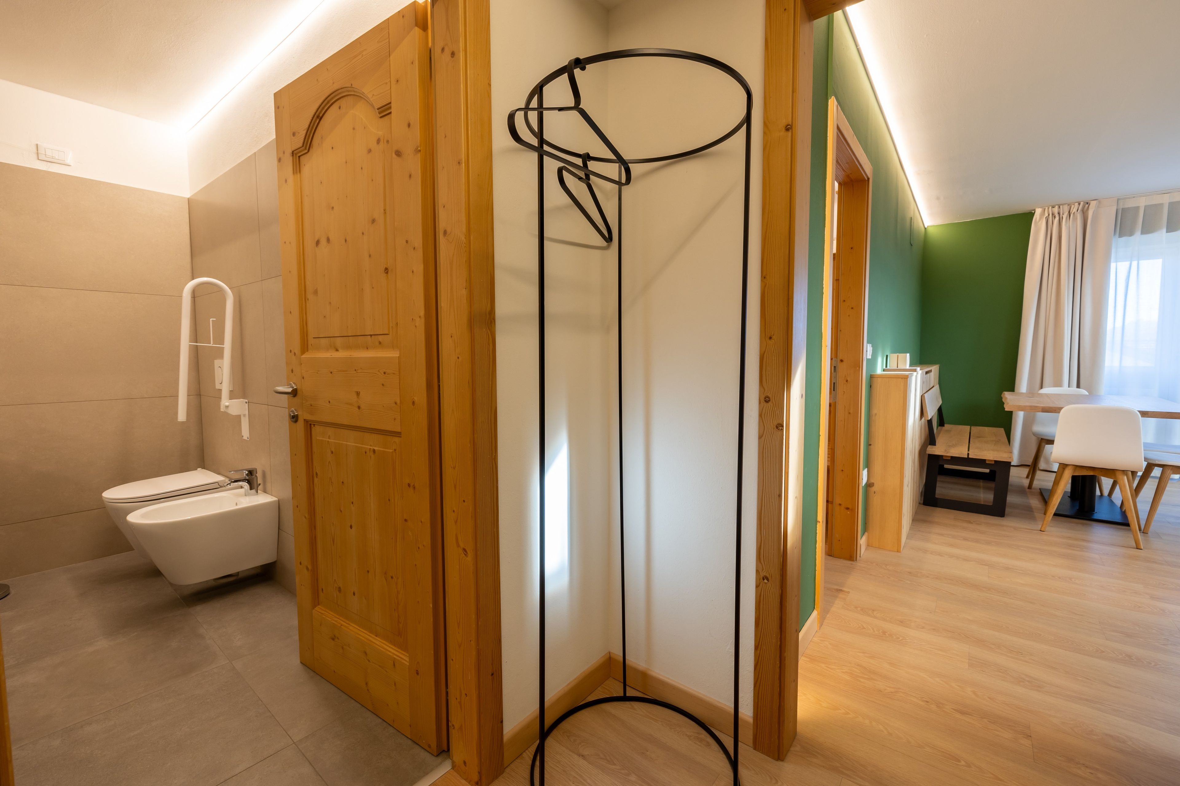Une salle de bain moderne avec une porte en bois, des toilettes blanches et un espace douche.