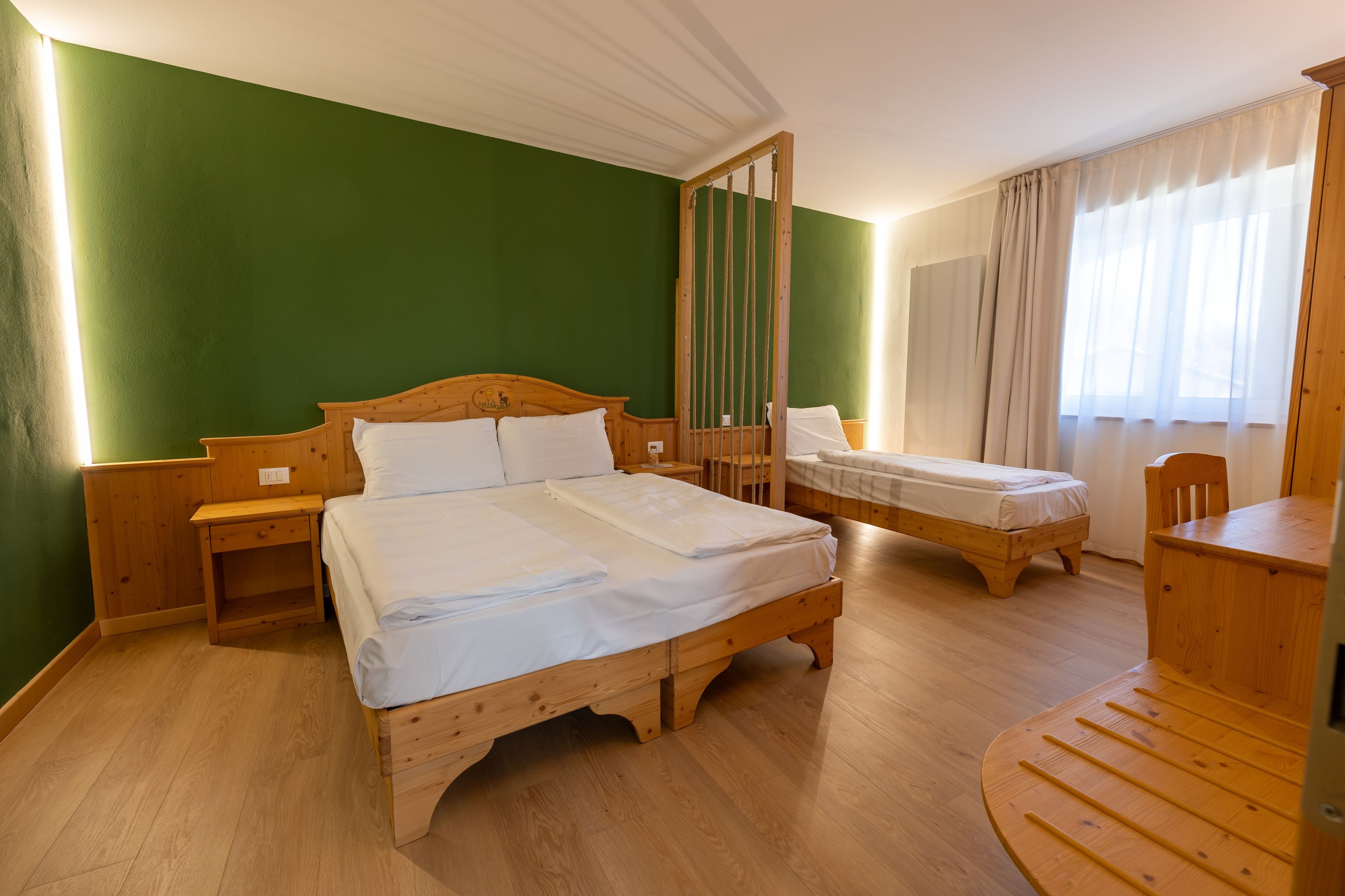 A room with two wooden beds, a wooden nightstand, a wooden table, and a chair.