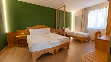 A room with two wooden beds, a wooden nightstand, a wooden table, and a chair.