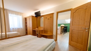 Quarto com cama, guarda-roupa de madeira, escrivaninha e cadeira.