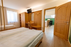 Ein Schlafzimmer mit einem Bett, einem Holzschrank, einem Schreibtisch und einem Stuhl.