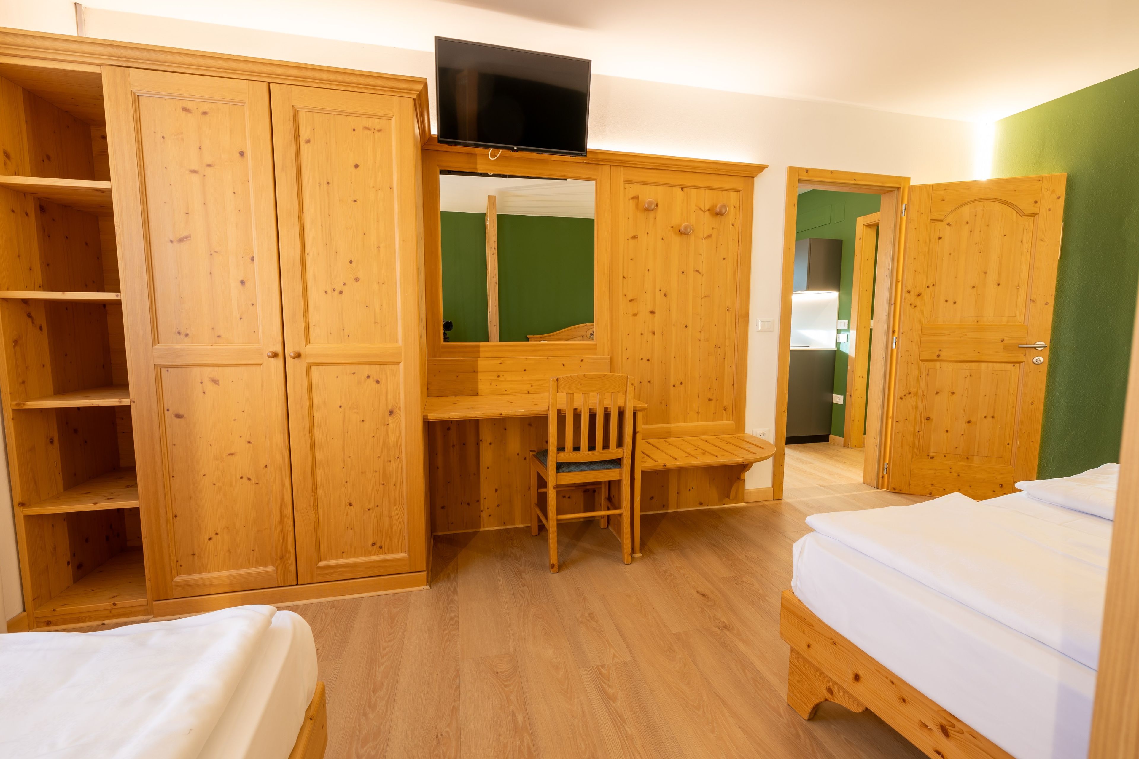 Ein Zimmer mit Holzmöbeln, einem Fernseher, einem Schreibtisch und einem Bett.