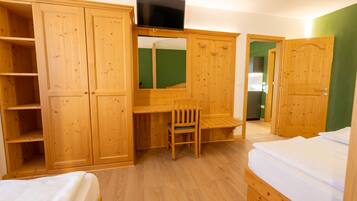Ein Zimmer mit Holzmöbeln, einem Fernseher, einem Schreibtisch und einem Bett.