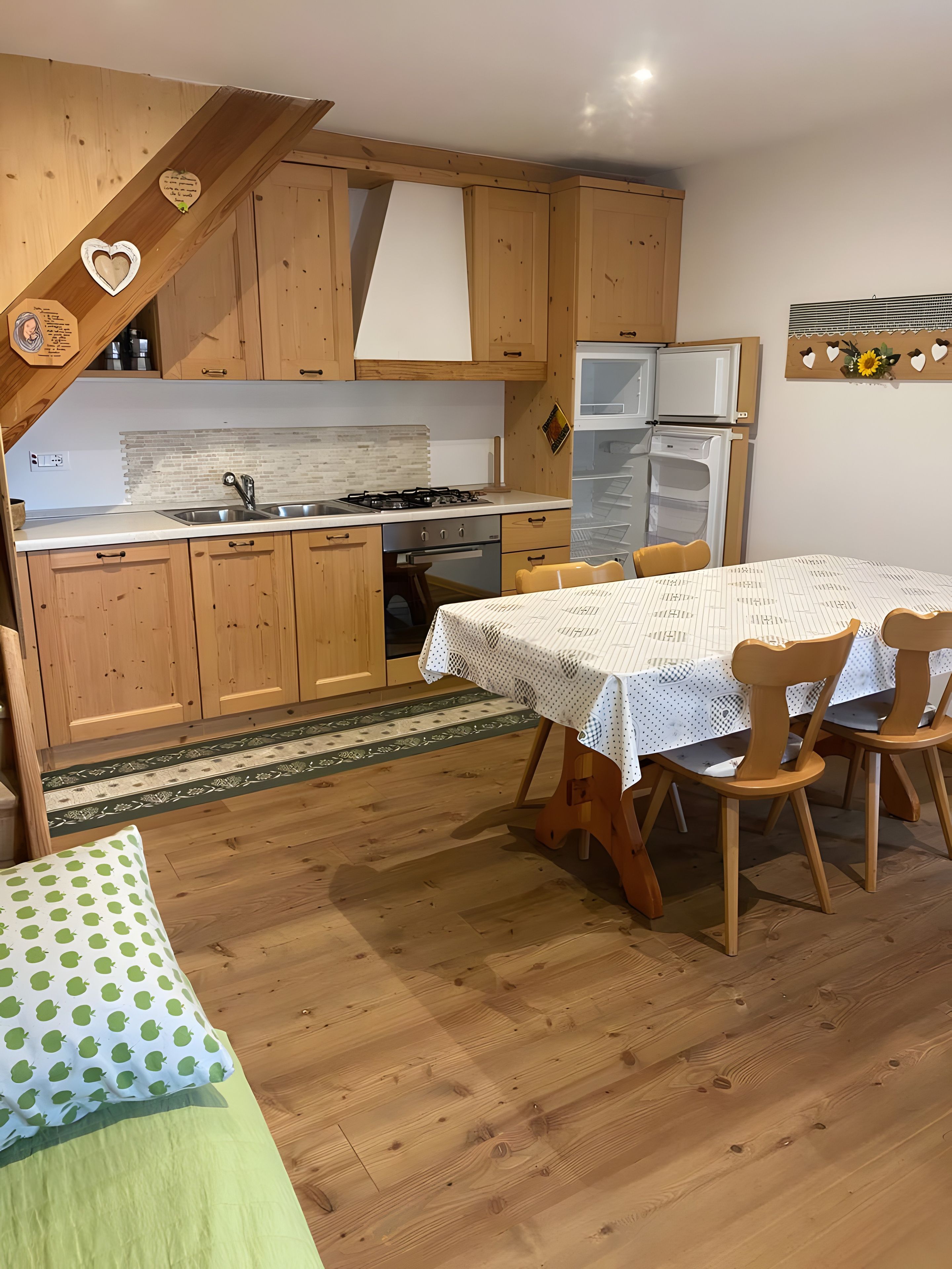 Eine Küche mit Holzausstattung, einem Esstisch mit Stühlen und einem Kühlschrank.