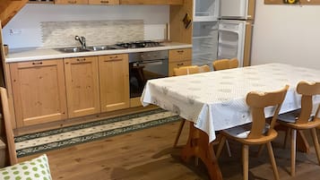 Eine Küche mit Holzausstattung, einem Esstisch mit Stühlen und einem Kühlschrank.