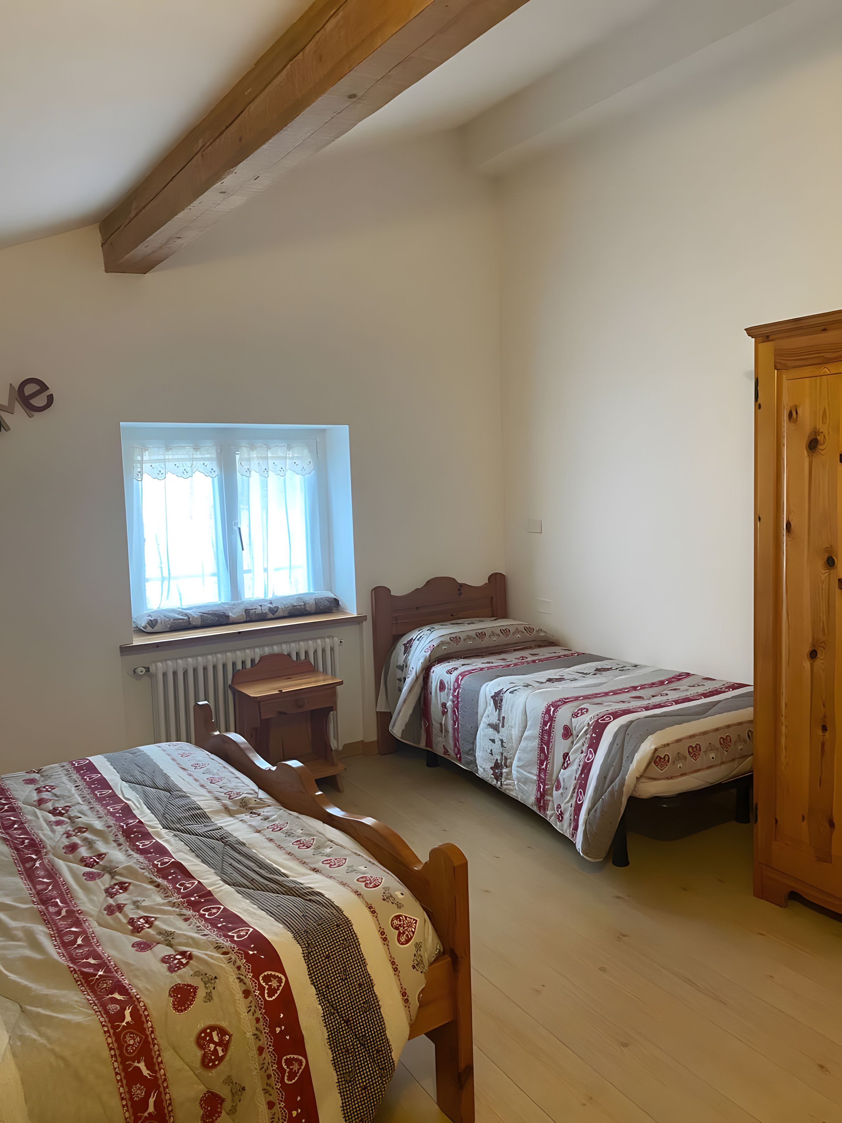 Un dormitorio con dos camas individuales, un armario de madera, un escritorio y una ventana con cortinas.