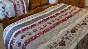 Un dormitorio con dos camas de madera, un armario, un televisor montado en la pared y una mesita de noche.