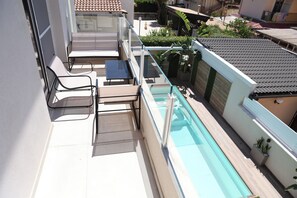 Ein Poolbereich auf dem Dach mit Liegestühlen und einer Glasbrüstung.