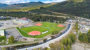 Vue aérienne d’un complexe sportif comprenant plusieurs terrains de baseball, un parking et une rivière qui le longe.