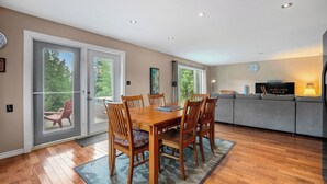 Un coin repas avec une table et des chaises en bois, un canapé et un téléviseur en arrière-plan.