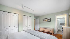 Une chambre à coucher comprenant un lit, une commode et une porte donnant sur une salle de bain.