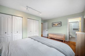 Een slaapkamer met een bed, een kaptafel en een deur naar een badkamer.