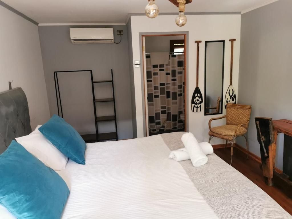 A hotel room with a bed, a chair, a small table, a mirror, and a door leading to a bathroom.