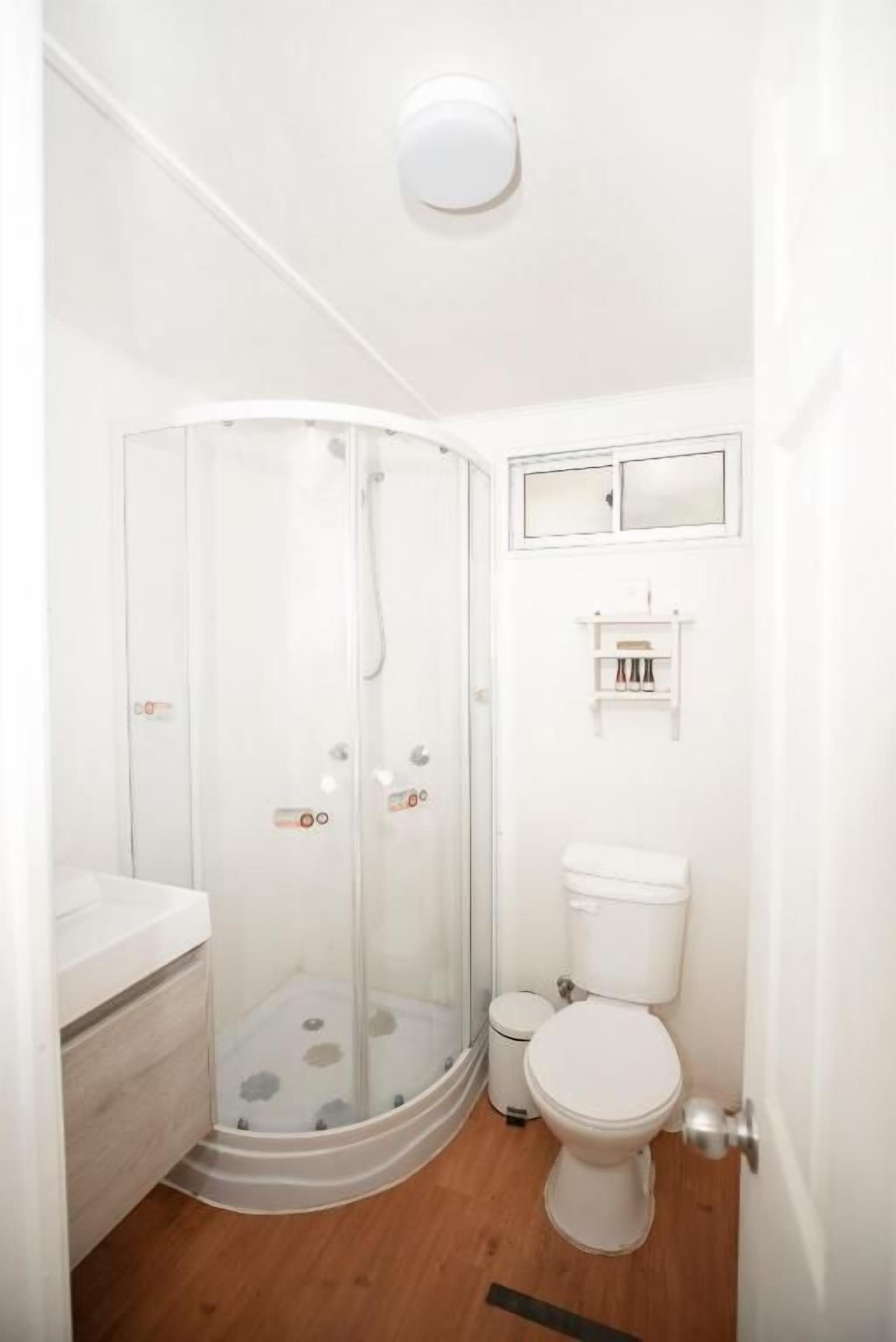 A bathroom with a glass-enclosed shower, a toilet, and a sink.
