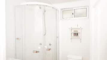 A bathroom with a glass-enclosed shower, a toilet, and a sink.