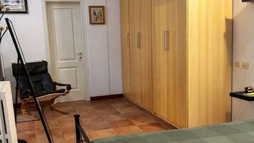 Ein Schlafzimmer mit Bett, einem Holzschrank, einem Sessel und einem Heizkörper.