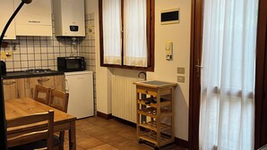 Cozinha compacta com mesa, cadeiras, micro-ondas, fogão e armário.