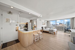 Eine moderne Wohnung mit Küche, Essbereich und Schlafzimmer mit Blick auf die Stadt.