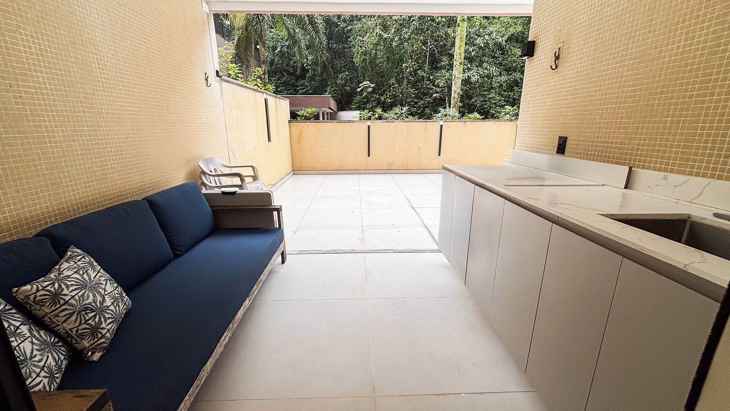 A compact kitchen with a built-in sink, a blue sofa, and a view of the outdoors.