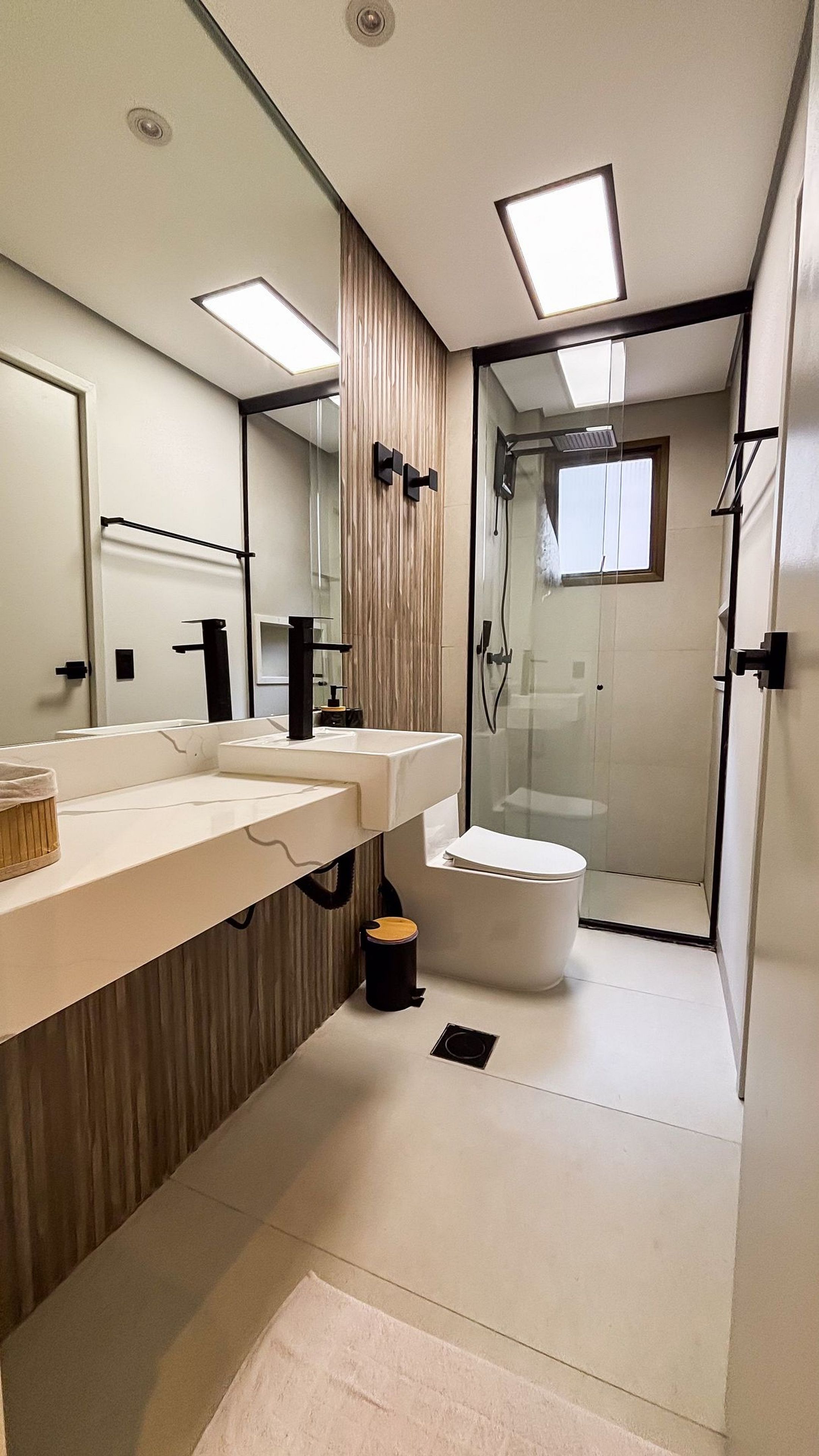Een moderne badkamer met een grote spiegel, twee wasbakken, een toilet en een douche met glazen wanden.