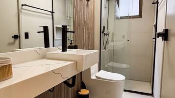 Een moderne badkamer met een grote spiegel, twee wasbakken, een toilet en een douche met glazen wanden.