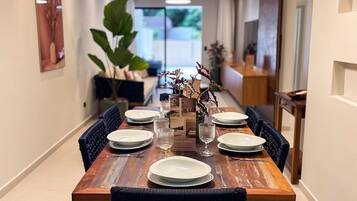 A dining table set with plates, glasses, and cutlery, flanked by chairs.