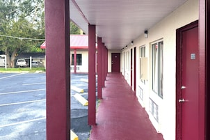 A motel corridor with red pillars, a covered walkway, and a parking lot.