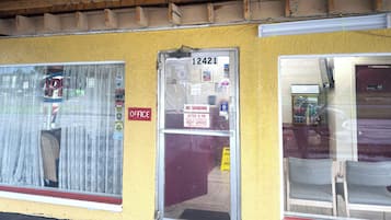 Um edifício com fachada amarela, porta com a inscrição 'OFFICE' e janela com aviso de 'NÃO FUMAR'.