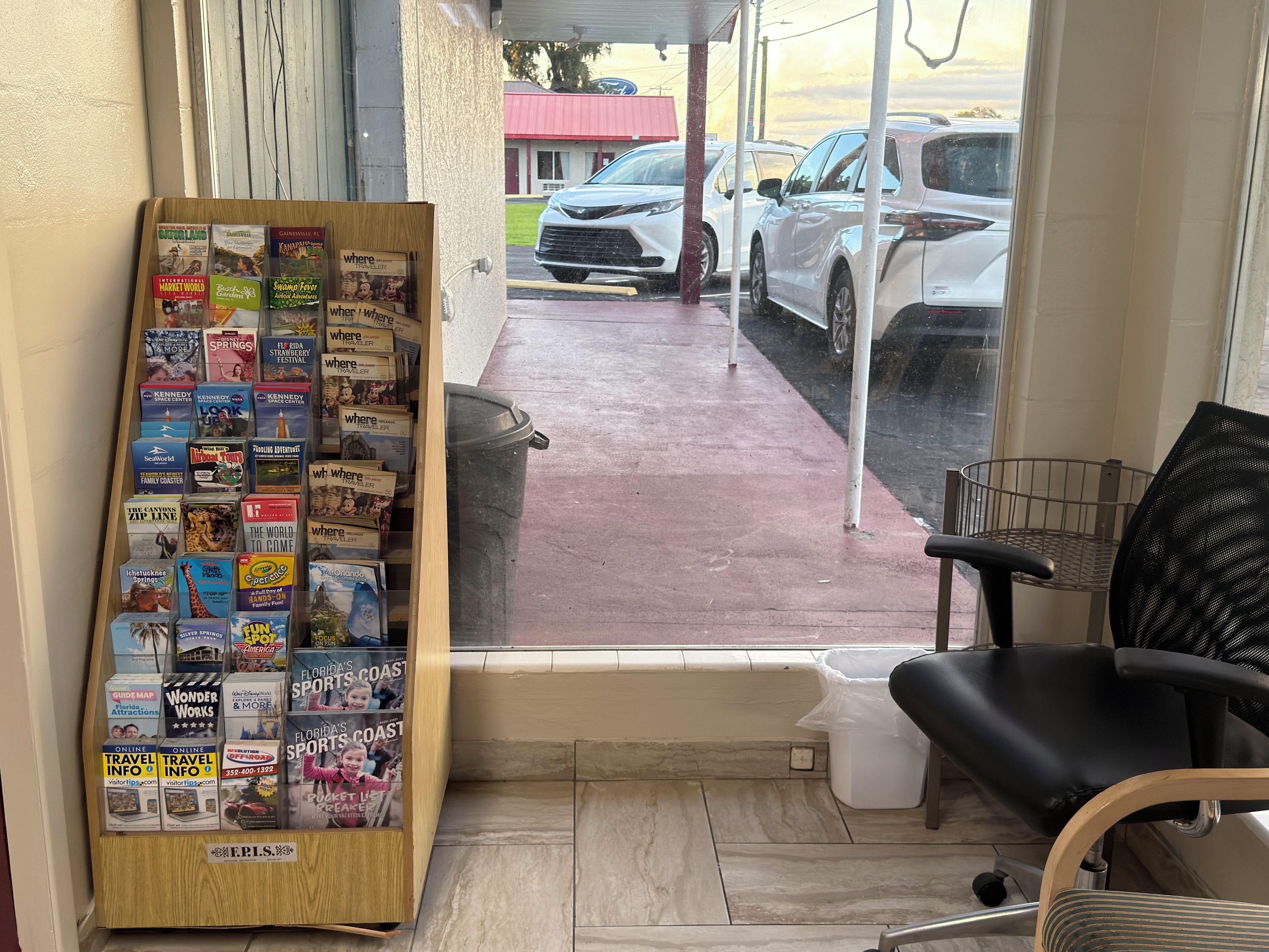 Un bureau d’information touristique doté d’un présentoir en bois où sont exposés divers guides de voyage et cartes.