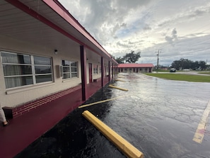 Un motel doté d’un parking couvert et d’un bâtiment à toit rouge.