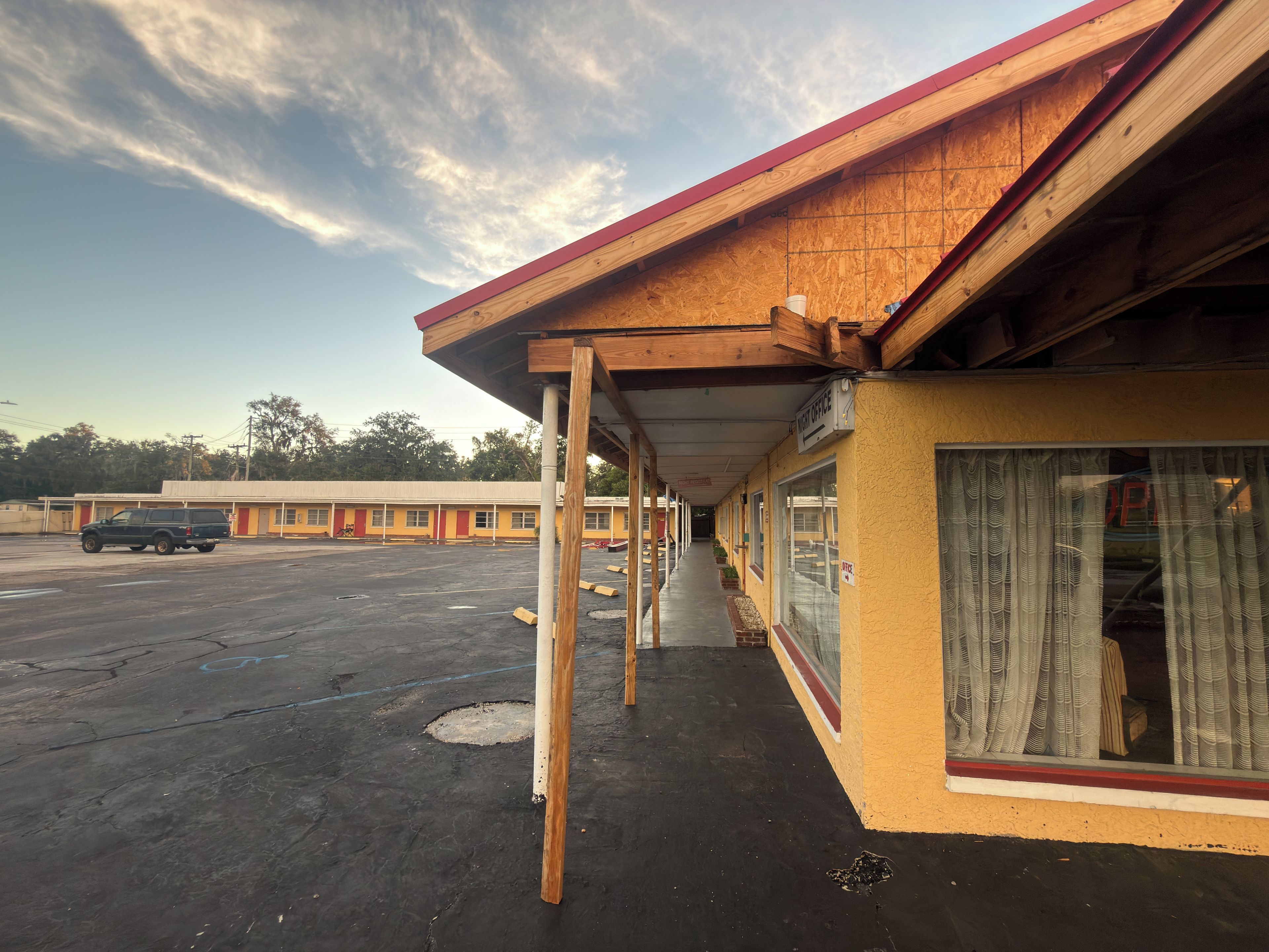Un motel doté d’un passage couvert, d’un parking et d’un bâtiment sur lequel est apposée une enseigne indiquant la présence de bureaux.
