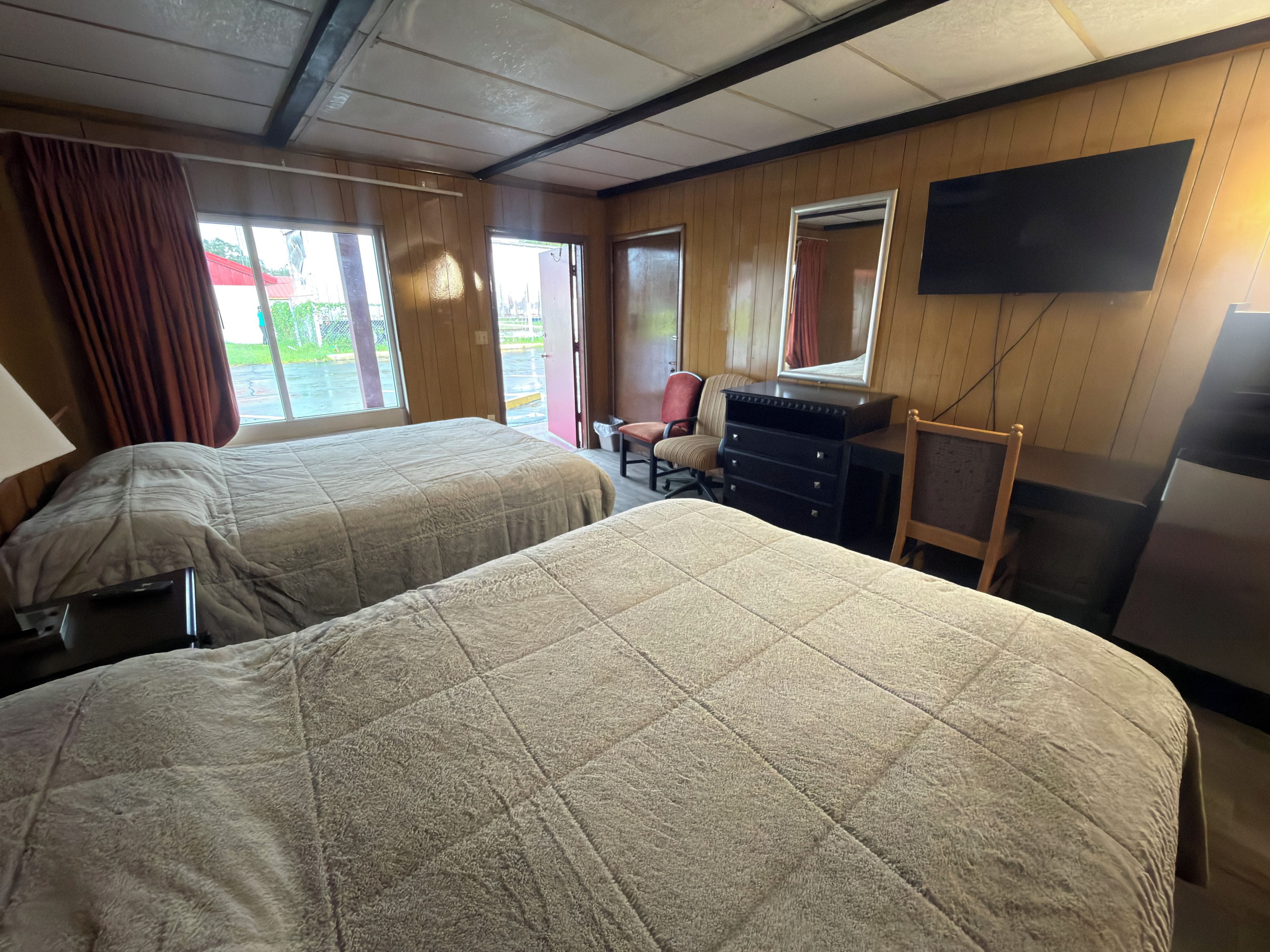 Une chambre d’hôtel avec deux lits, un bureau, une chaise, une commode et un téléviseur.