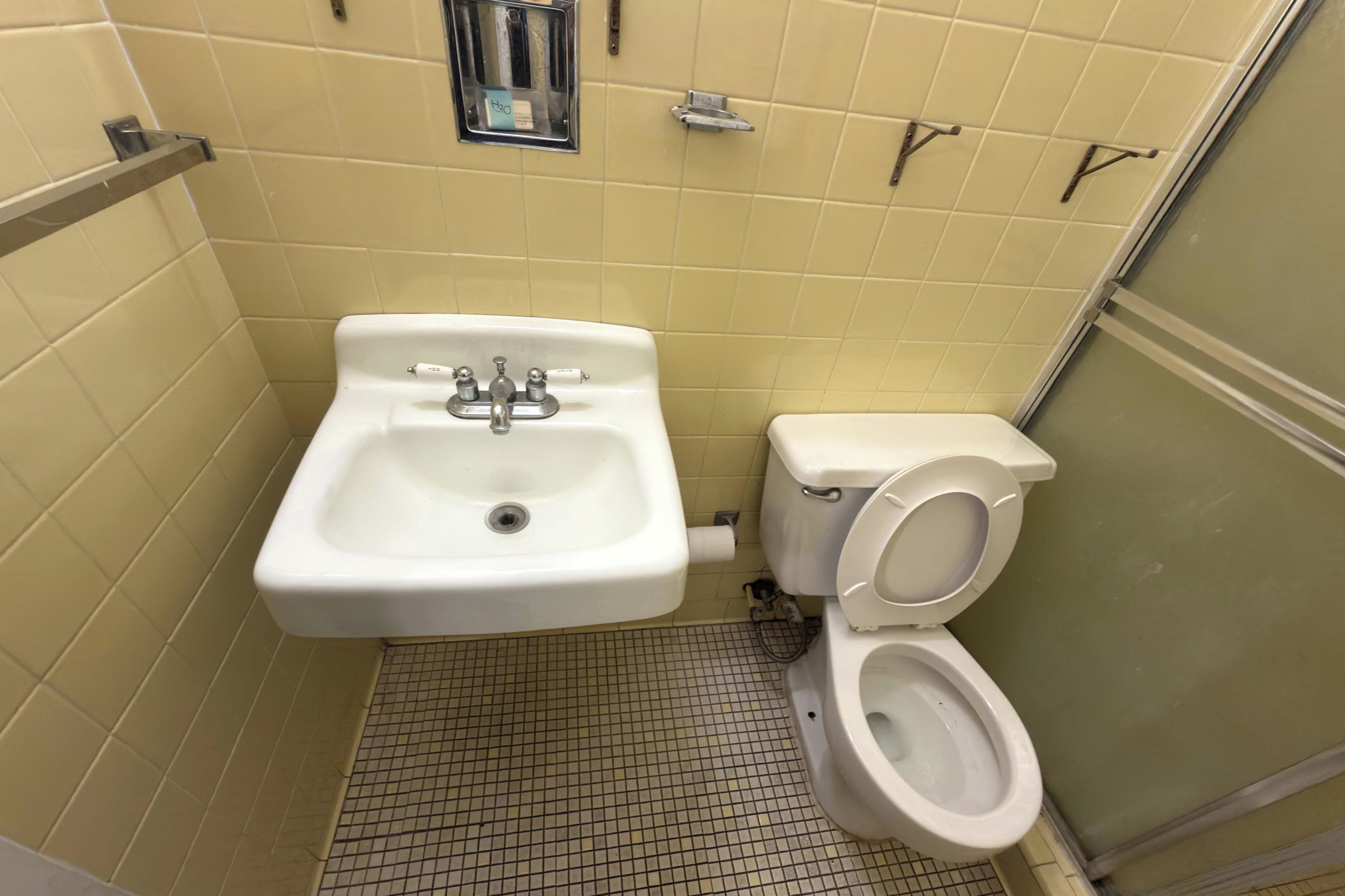 A small bathroom with a sink, toilet, and a shower stall.