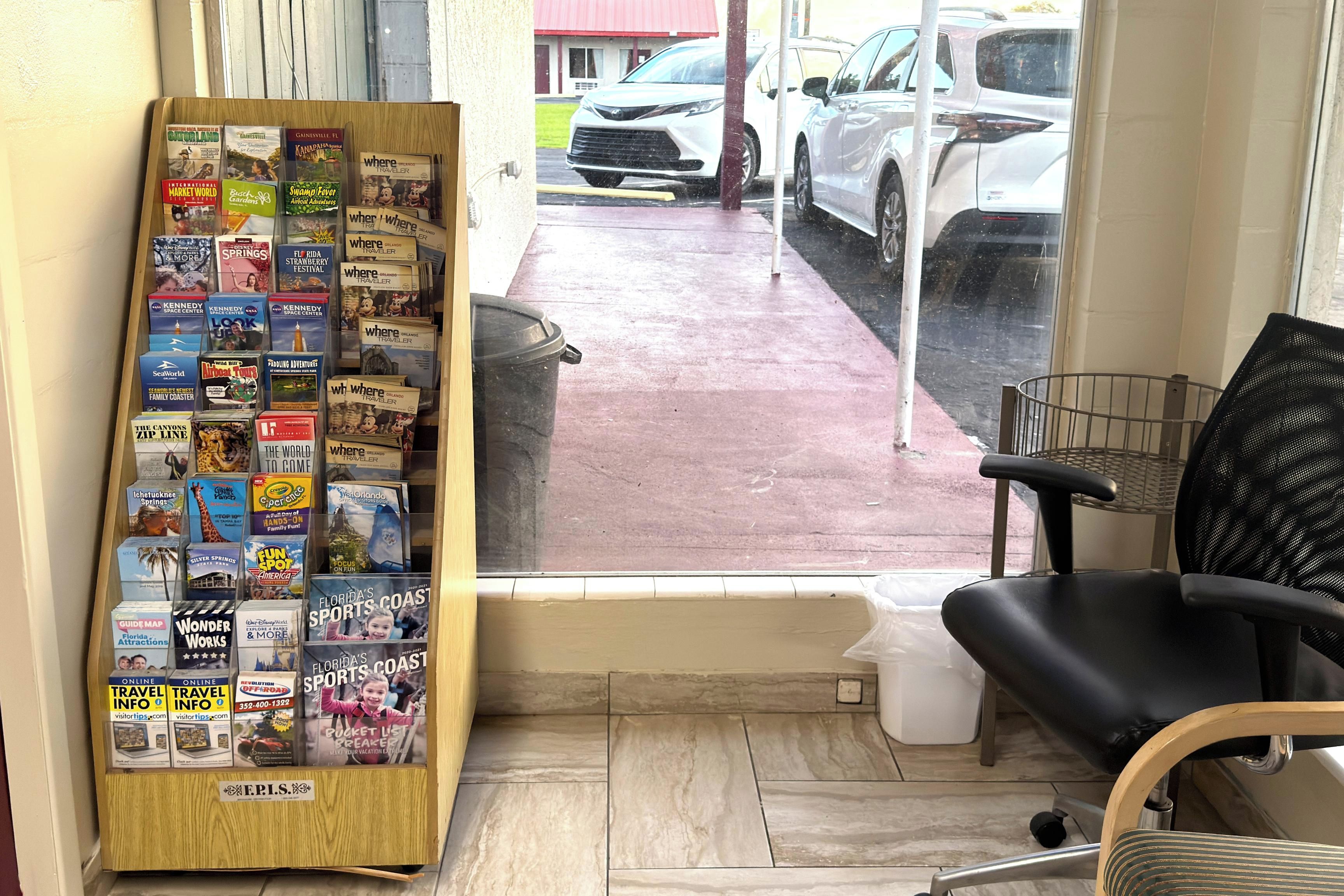 Oficina de una agencia de viajes con un expositor de folletos turísticos y una silla de escritorio negra.