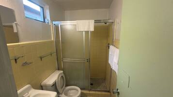 Un baño con inodoro, lavamanos y cabina de ducha.