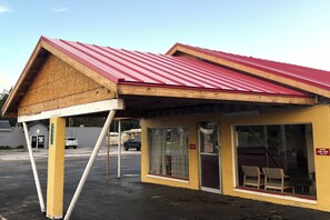 A small building with a red roof, a wooden facade, and a glass door labeled 'Office'.