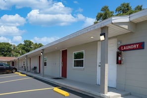A building with a laundry facility, a covered parking area, and a clear sky.
