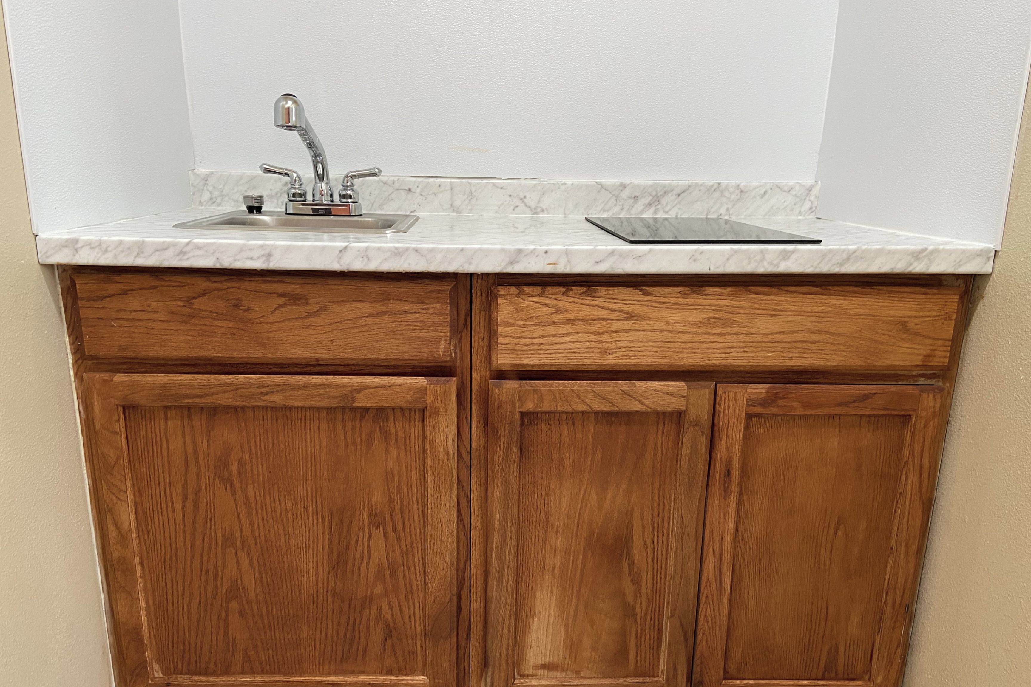 Una cocina con un lavamanos, armarios de madera y encimera de mármol.
