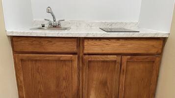 Una cocina con un lavamanos, armarios de madera y encimera de mármol.