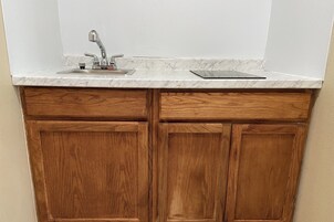 Una cucina con un lavello singolo, mobili in legno e un piano di lavoro in marmo.