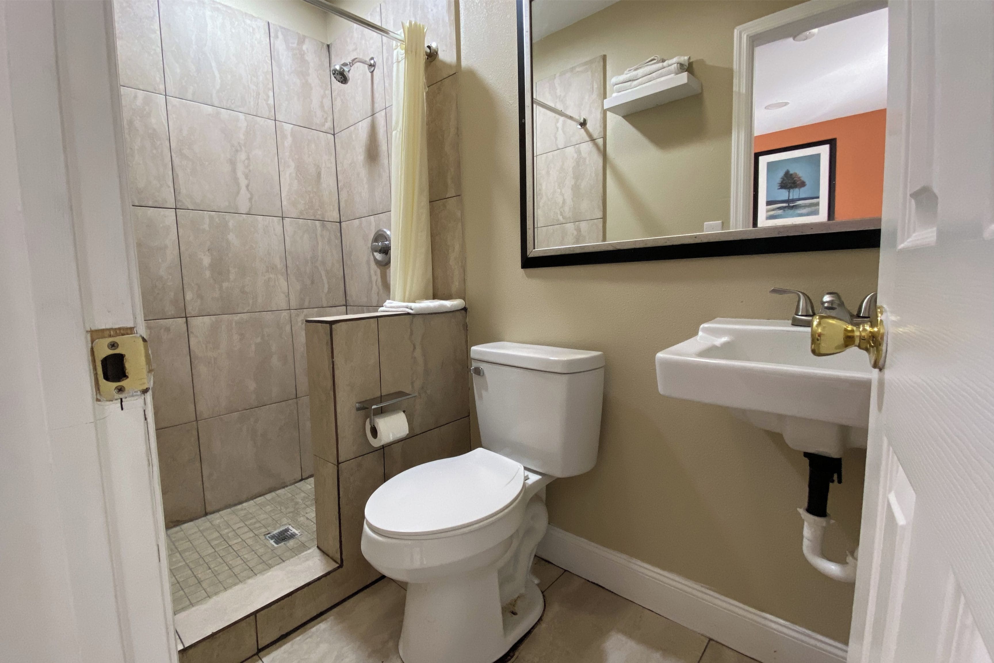 Une salle de bain avec douche, toilettes et lavabo.