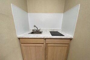 A compact kitchen with a sink, a stove, and wooden cabinets.
